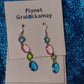 Multi Colored Drop Earrings. Made with a surgical steel hook. The earrings are made up of four different plastic jewels green, dark blue, light blue and pink