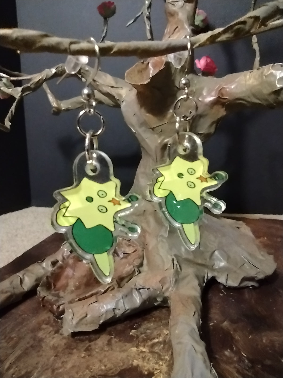 A pair of Green Larcunight earrings hanging on a paper Mache tree.  