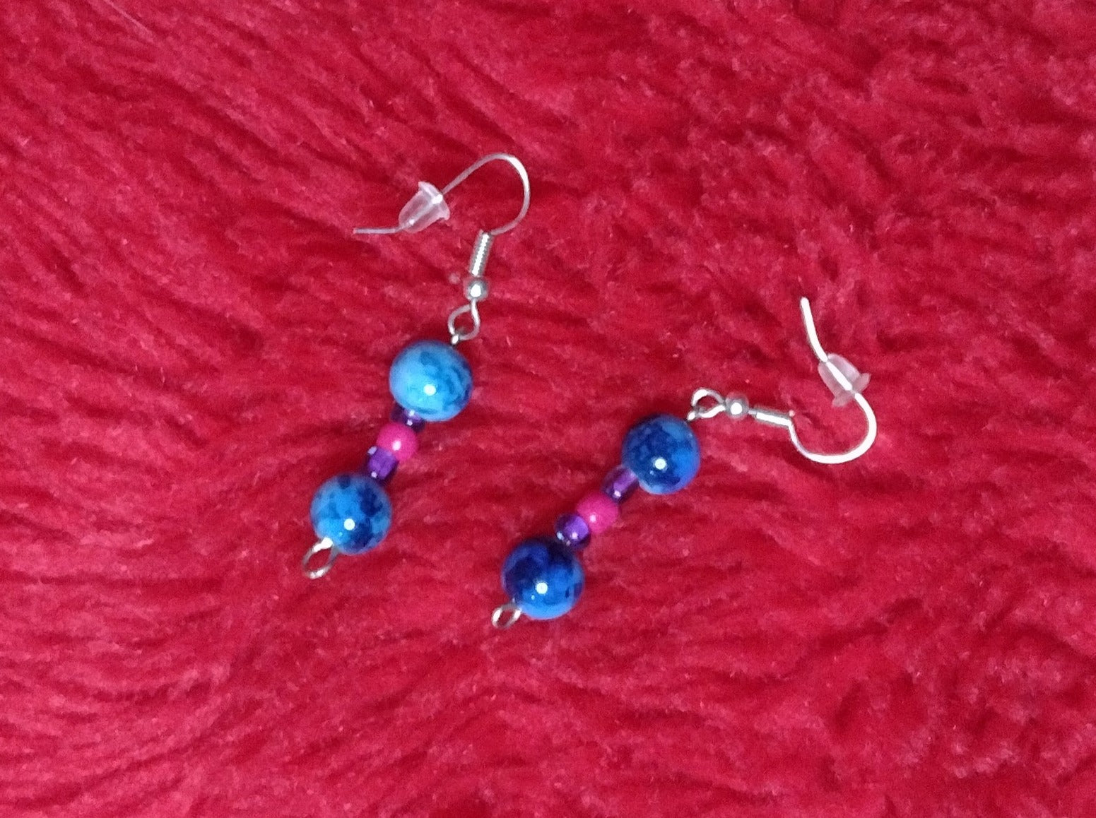 Blue Drop Earrings with two blue speceld beads one on the top and bottom. In between is a transparent small purple bead then a magenta glass bead and a purple glass bead.